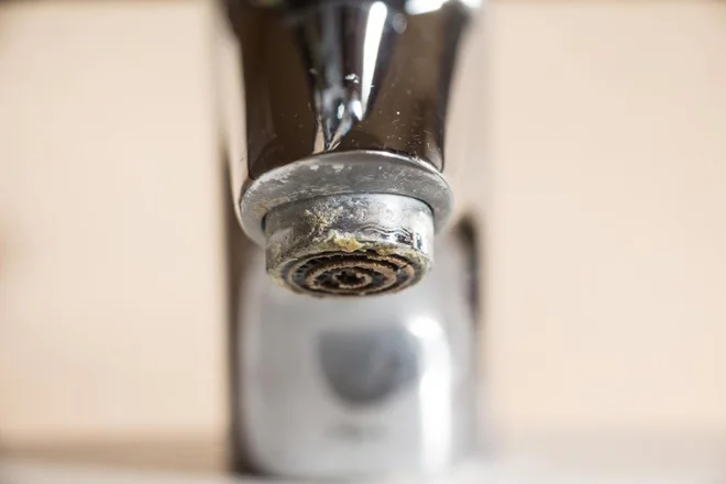 Voda v Sloveniji vsebuje precej vodnega kamna, kar lahko opazimo v obliki belih lis na pipah, nabira pa se tudi v likalniku. Foto: Shutterstock