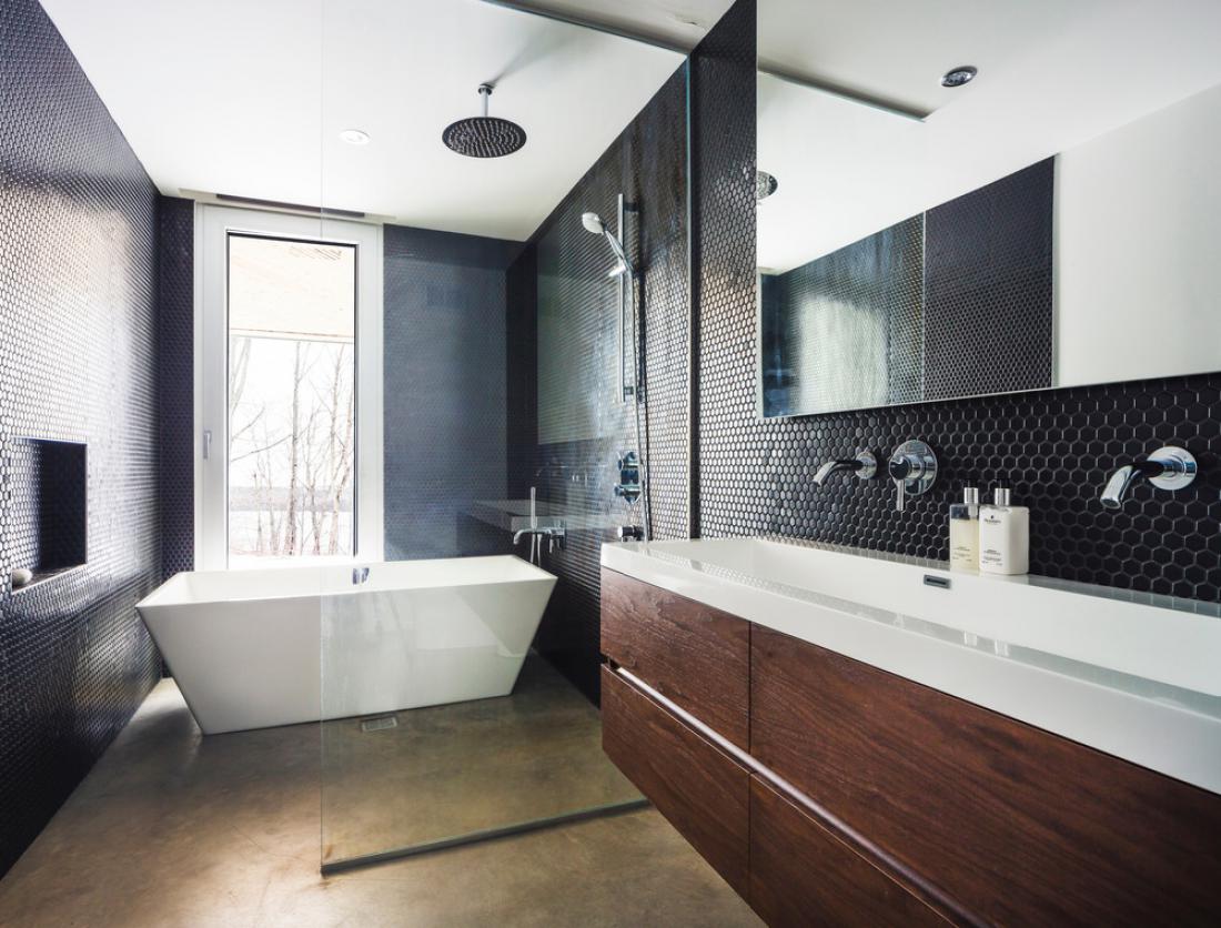 Razkošnost kopalnice poudarjajo črne mozaične ploščice, temen orehov les in prosto stoječa kad.