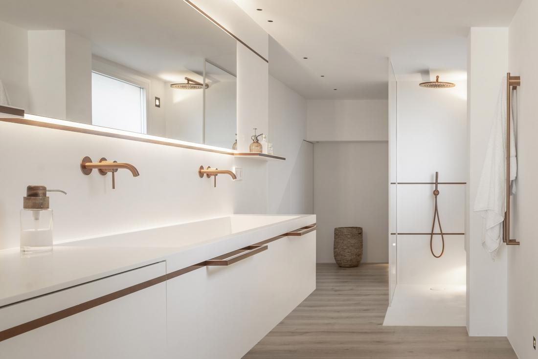 Popolnoma belo kopalnico kot nakit dopolnjujejo bakrene armature, svetila in ročaji.