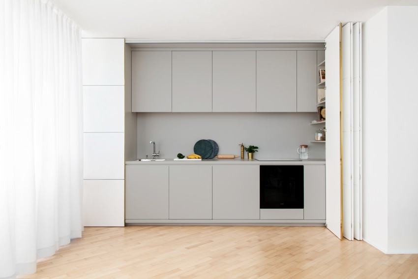 Spremenljivi značaj stanovanja se kaže v vgradni kuhinji, ki se lahko s sestavljivimi frontami zapre in je videti kot mrežasta stenska obloga s poudarjenim vertikalnim medeninastim ročajem.
