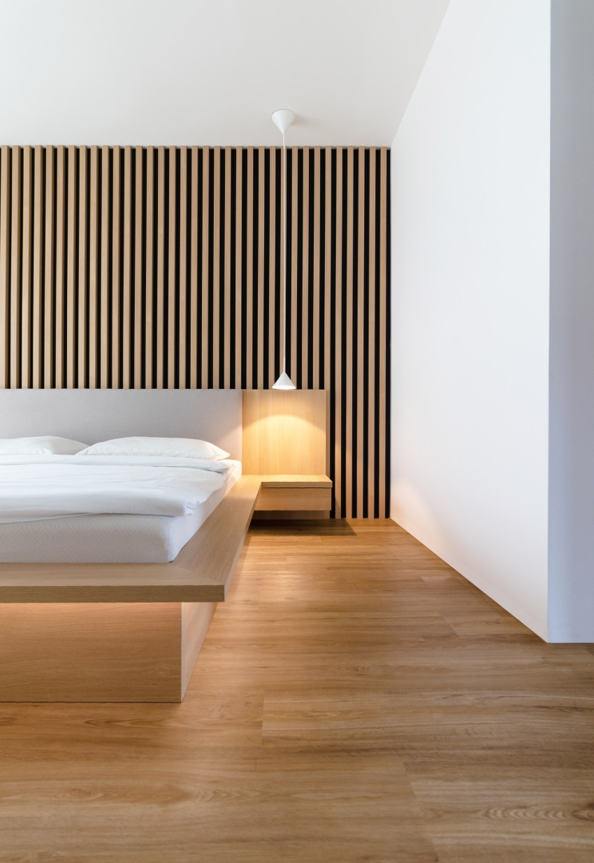 <p>Za vzglavjem postelje je stena v lesu, ki je oblikovana kot platno lesenih lamel.</p>