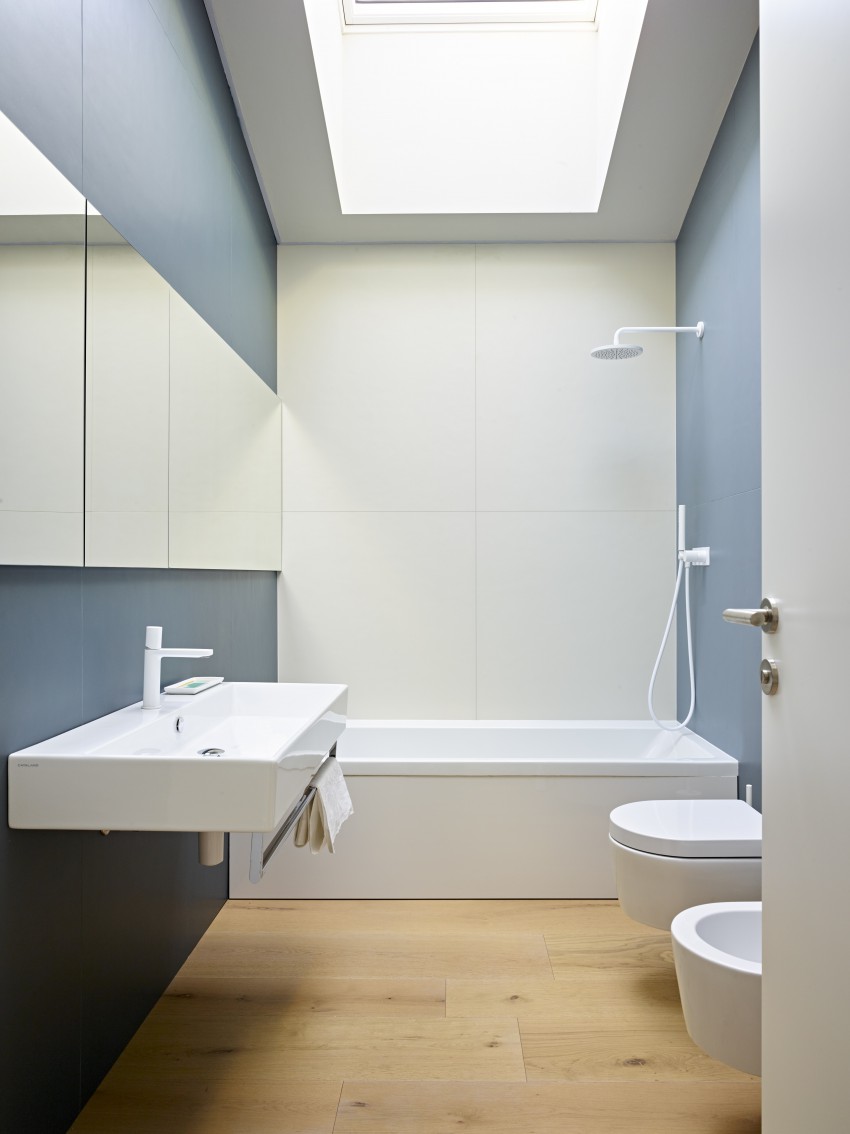 <p>Druga kopalnica ima stene popleskane v sivomoder odtenek, tudi v tej so preostali elementi beli, tla pa lesena.</p>