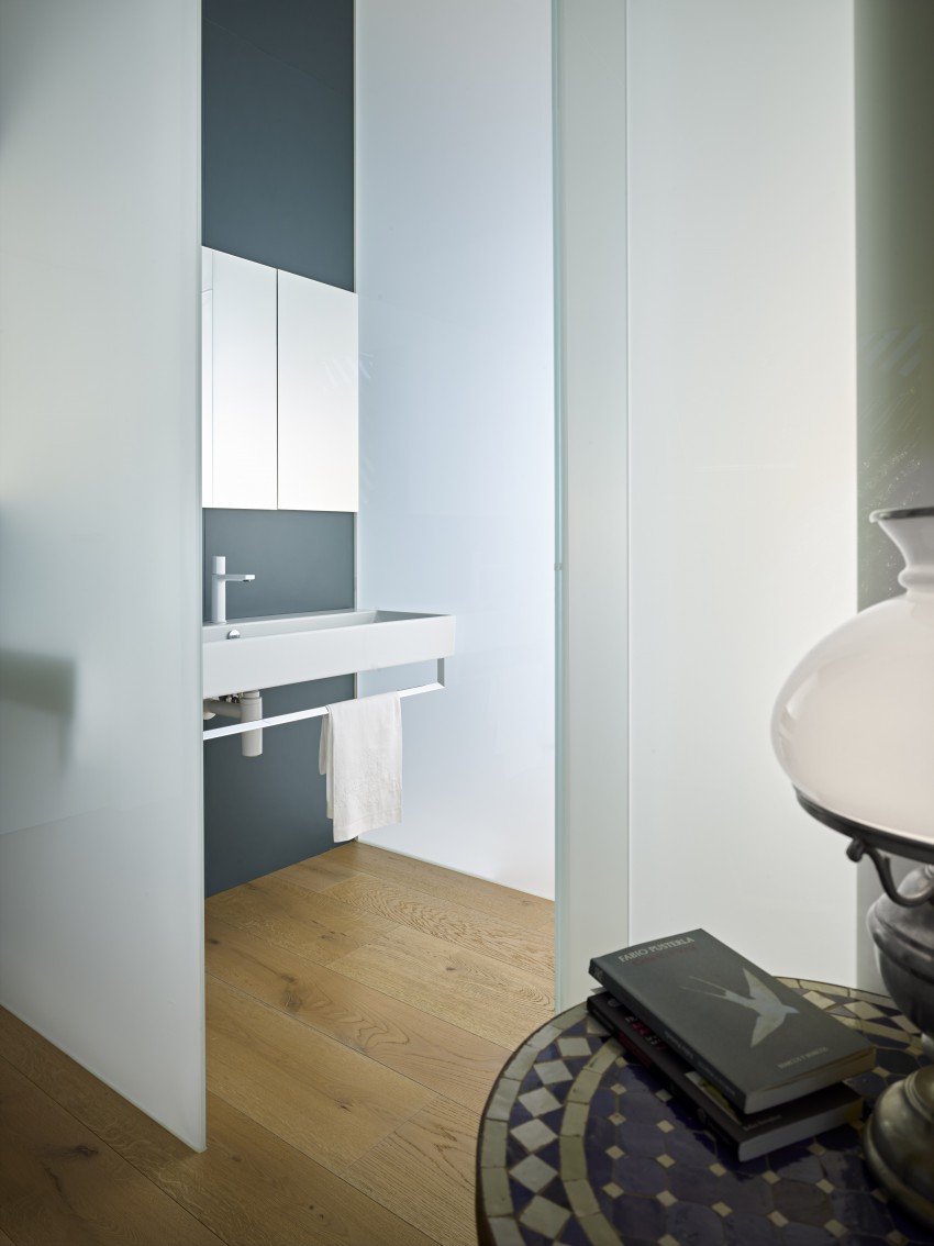 <p>Kontrast sivi steni v kopalnici so beli kopalniški elementi in bele armature.</p>
