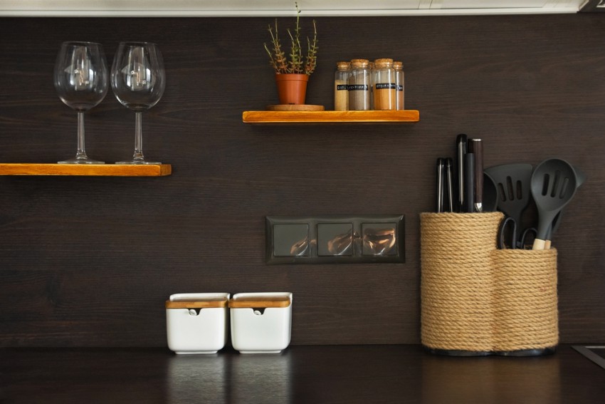 <p>Temno steno v kuhinji lahko poživite s policami v svetlejšem lesu in dodatki.</p>