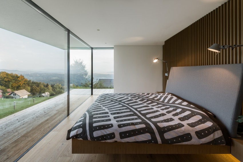 Pritličje, v katerem so spalnice, obkroža zunanji lesen pohodni venec, ki hišo poveže z zeleno okolico.