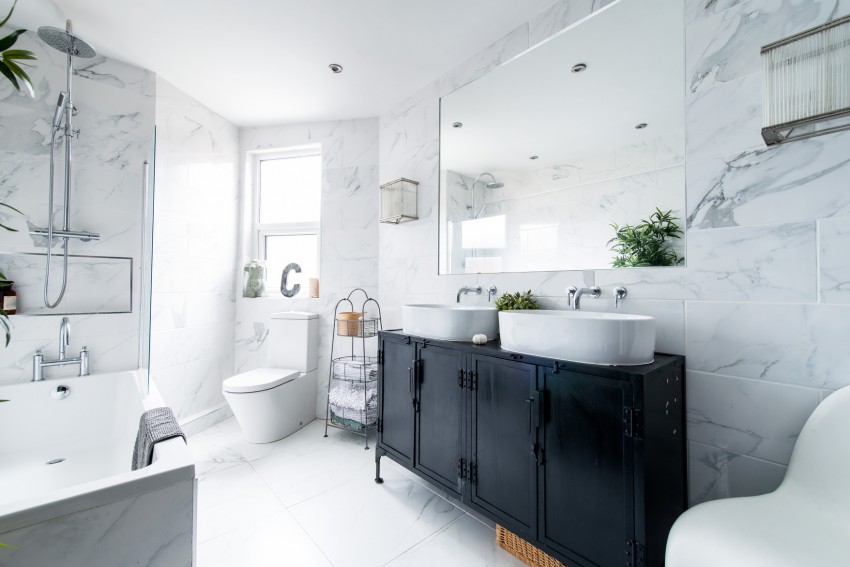 Sodobna kopalnica, odeta v keramične ploščice velikih mer, ki posnemajo videz marmorja.