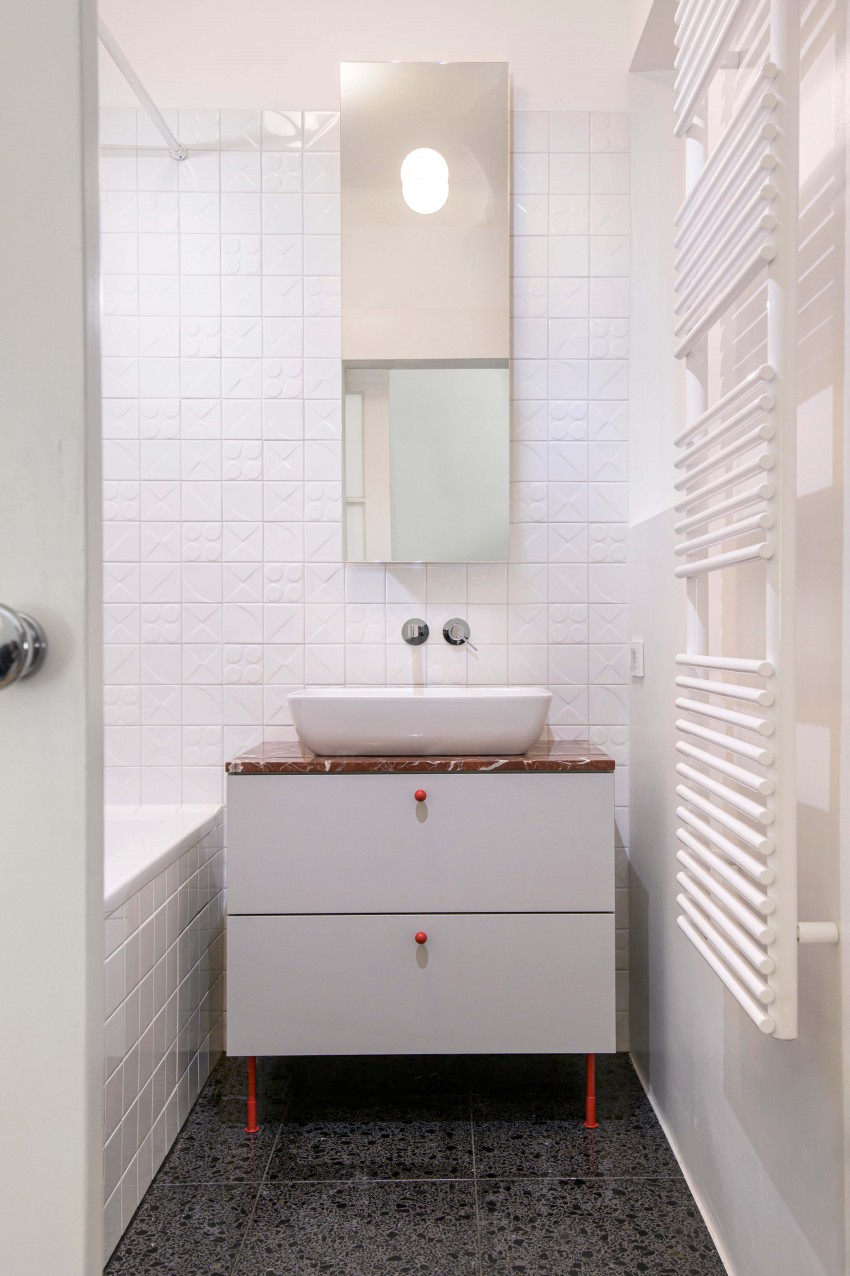 <p>Za tlake sanitarnih prostorov je arhitektka izbrala temen terazzo, za stene pa belo oljnato barvo v kombinaciji s keramiko, oblikovano v petdesetih letih.</p>