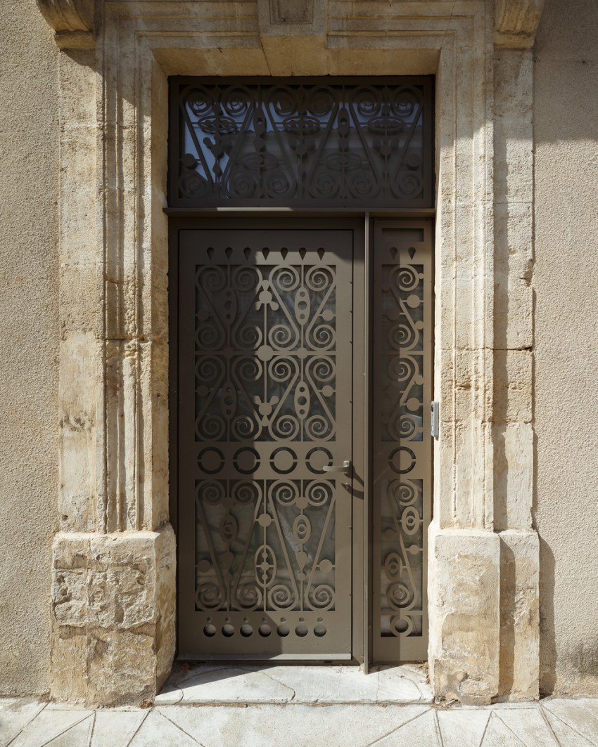 <p>Visoki kamniti portal nekdanje stanovanjske hiše je dobil sodobno dopolnitev: perforirana kovinska vrata.</p>